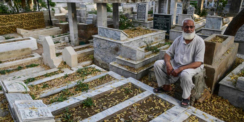 1 مارچ 2022 کو لی گئی اس تصویر میں، محمد اسلم، کراچی کے طارق روڈ قبرستان میں ایک رشتہ دار کی قبر کے پاس بیٹھے ہیں۔- اے ایف پی