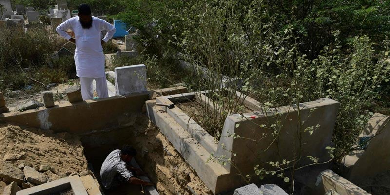 2 مارچ 2022 کو لی گئی اس تصویر میں، ایک قبر کھودنے والا کراچی کے ایک رہائشی علاقے کے قریب کورنگی قبرستان میں ایک نئی قبر بنا رہا ہے۔  - اے ایف پی