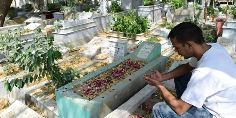 1 مارچ 2022 کو لی گئی اس تصویر میں، محمد عبداللہ سیف کراچی کے طارق روڈ قبرستان میں اپنے باپ کی قبر کے پاس نماز ادا کر رہے ہیں۔  — اے ایف پی/فائل