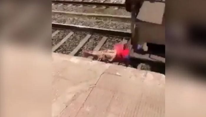 Woman lies on tracks as train passes over her. Screengrab via Twitter/@ipskabra