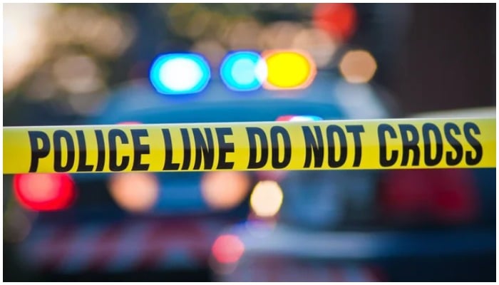 Representational image of a crime scene showing a barricade tape against the blurred image of a police car. — Twitter