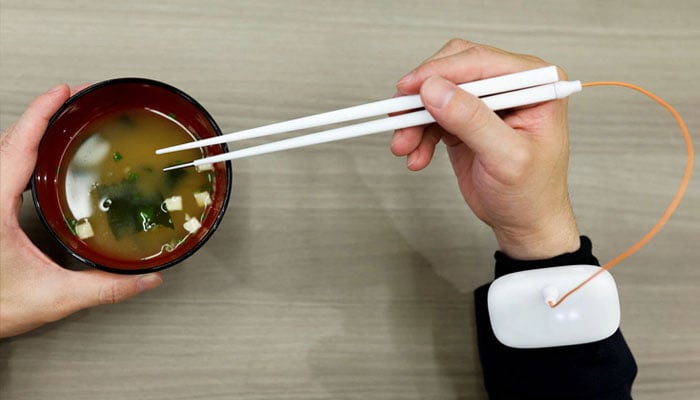 An employee of Kirin Holdings demonstrates chopsticks that can enhance food taste using an electrical stimulation waveform that was jointly developed by the company and Meiji Universitys School of Science and Technology Professor Homei Miyashita, in Tokyo, Japan April 15, 2022. Photo— REUTERS/Issei Kato