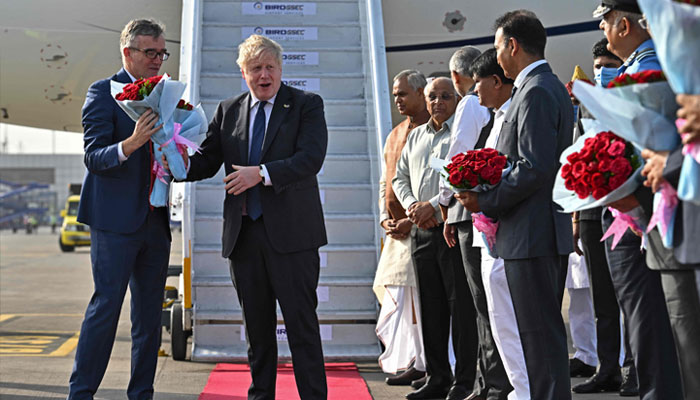 Britains Prime Minister Boris Johnson (C) is greeted by officials upon his arrival at the airport in Ahmedabad on April 21, 2022. — AFP