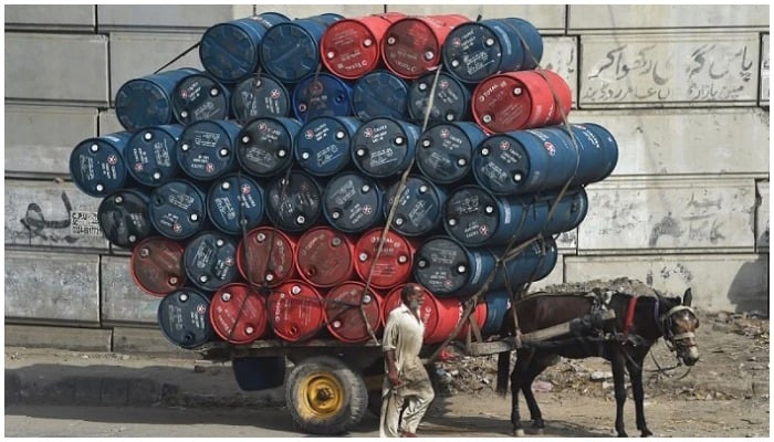 A man stands next to a horsecart laden with oil drums on a street in Lahore. — AFP/ file
