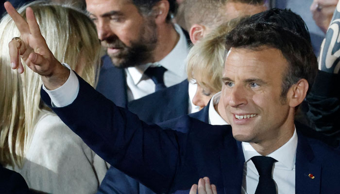 French President and La Republique en Marche (LREM) party candidate for re-election Emmanuel Macron flashes the V-sign as he greets supporters after his victory in France´s presidential election, at the Champ de Mars in Paris, on April 24, 2022. Photo — Ludovic MARIN / AFP
