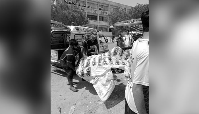 26 اپریل 2022 کو کراچی یونیورسٹی میں وین دھماکے کے بعد امدادی کارکن ایک جاں بحق شخص کی لاش کو منتقل کر رہے ہیں۔ — Twitter/ahmed2_syed