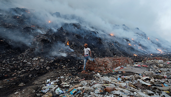 18 سالہ شیخ شاہدول 27 اپریل 2022 کو نئی دہلی، انڈیا میں بھلسوا لینڈ فل سائٹ پر جلتے ہوئے کچرے سے گزر رہے ہیں۔ — رائٹرز