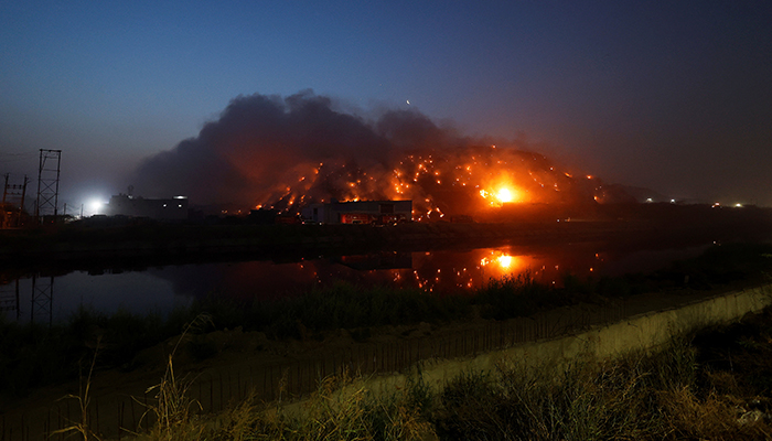 Fire trucks are seen on a road as smoke billows from burning garbage at the Bhalswa landfill site in New Delhi, India, on April 27, 2022. — Reuters