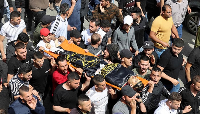 Palestinian mourners carry the body of Ahmad Massad during his funeral in the village of Burqin, west of Jenin in the occupied West Bank, on April 27, 2022. — AFP
