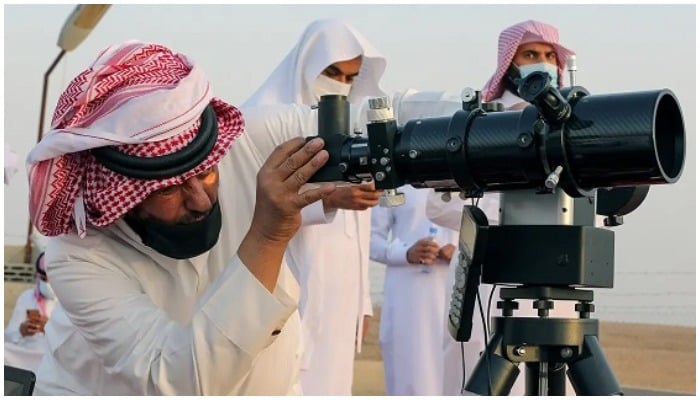 Seorang pria melihat melalui teleskop untuk melihat bulan sabit.  - Indonesia