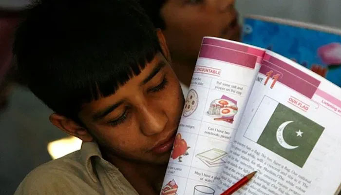 A boy pointing toward Pakistans flag in his book. — Reuters/File