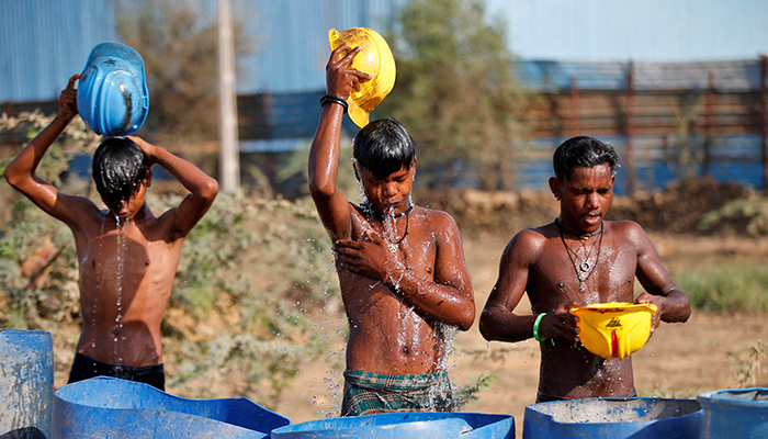 Workers use their helmets to pour water to cool themselves off near a construction site on a hot summer day on the outskirts of Ahmedabad, India, on April 30, 2022. — Reuters