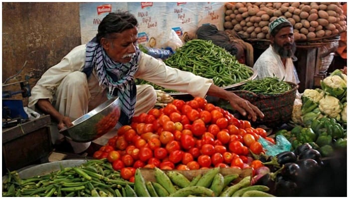 A vegetable vendor weighs vegetables at a stall. — Reuters