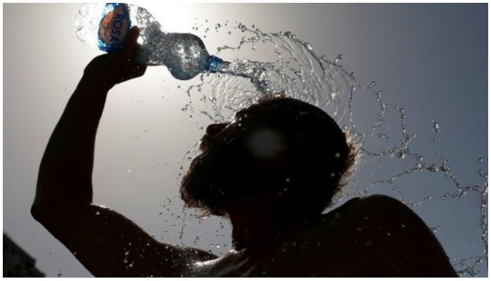 A man pours water on his face to cool off from hot weather. — Reuters/ file