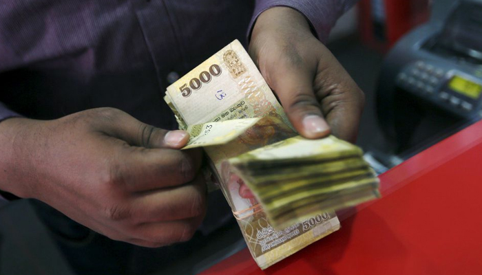 A man counts Sri Lankan rupees at a money exchange counter in Colombo on September 4, 2015. — Reuters