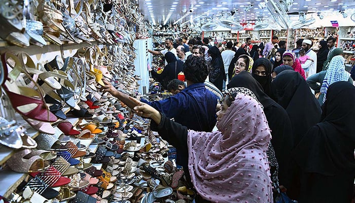 خواتین یکم مئی 2022 کو کراچی کی حیدری مارکیٹ میں عید الفطر کے لیے جوتے خریدنے میں مصروف ہیں۔ - اے پی پی