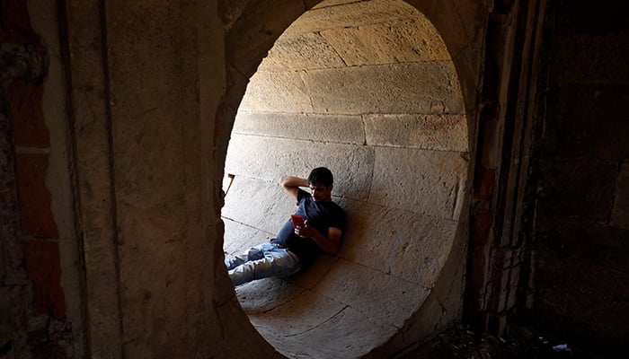 A man rests in a dry water tunnel of the Sarkhej Roza lake during hot weather in Ahmedabad, India, on April 28, 2022. — Reuters