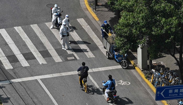 Policemen check delivery workers on scooters on the street during a COVID-19 coronavirus lockdown in the Jingan district in Shanghai on May 2, 2022. — AFP