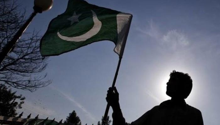 The picture shows a silhouette of a man holding a Pakistani flag. — Reuters/File