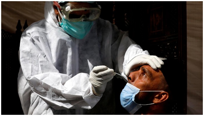 A paramedic wearing protective gear takes a nose-swab sample to be tested for the coronavirus in Karachi. — Reuters/ file