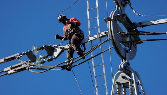 A technician works on a double 400.000 high voltage power line during the installation of spacers on new electrical pylons named Equilibre in Courcelles-les-Lens, near Douai, France, November 18, 2020.—Reuters