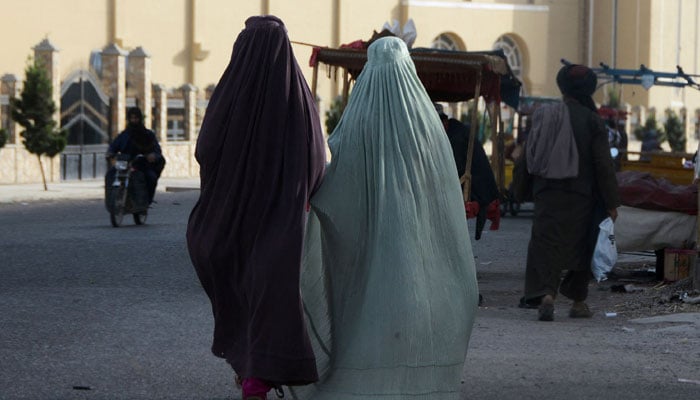Burqa-clad women walk along a street in Kandahar on May 7, 2022. —AFP