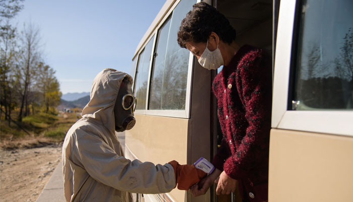 In this file photo a ´hygienic and anti-epidemic official´ checks the body heat of a traveller aboard a bus.North Korea on May 12, 2022 confirmed its first-ever case of COVID-19, with state media declaring it a severe national emergency incident after more than two years of purportedly keeping the pandemic at bay. Photo— KIM Won Jin / AFP