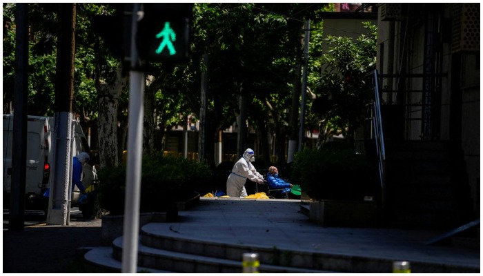 worker in a protective suit helps an old man with a wheelchair during lockdown amid the coronavirus disease (COVID-19) pandemic, in Shanghai, China, May 5, 2022. — Rueters