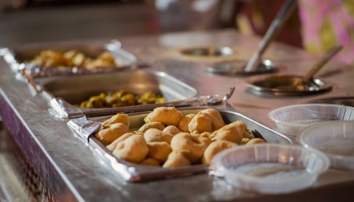 Crowd marches towards wedding food as the waiters open the lids. — Unsplash/@Reubx