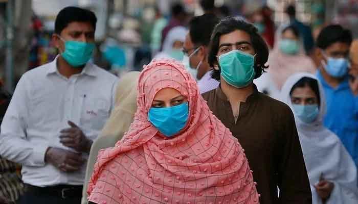 Masked people walk in a market amid the fourth wave of the coronavirus pandemic in Pakistan. — AFP/File