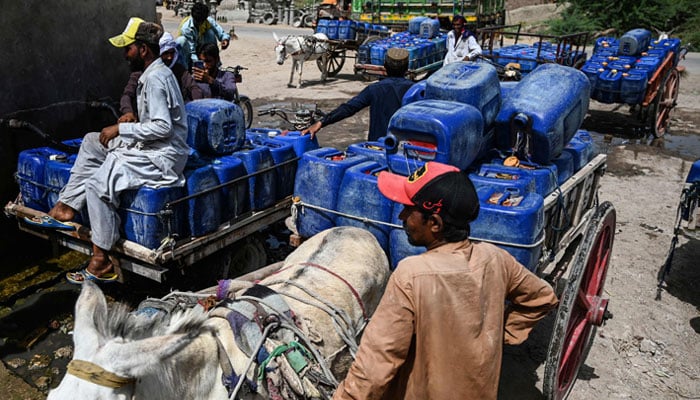 In this picture taken on May 11, 2022, vendors fill cans with drinking water from a water supply plant for selling during heatwave in the Pakistans hottest city of Jacobabad in southern Sindh province. — AFP