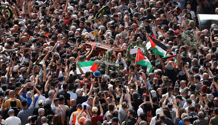 Palestinian mourners wave national flags as they carry the casket of slain Al-Jazeera journalist Shireen Abu Akle, during her funeral procession near Jaffa Gate, one of the main gates of the Old City of Jerusalem, on May 13, 2022. — AFP