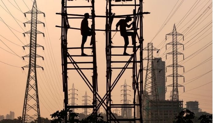 Laborers work next to electricity pylons in Mumbai, India, October 13, 2021.—Reuters