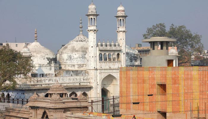 A worker stands on a temple rooftop adjacent to the Gyanvapi Mosque in the northern city of Varanasi, India, on December 12, 2021. — Reuters