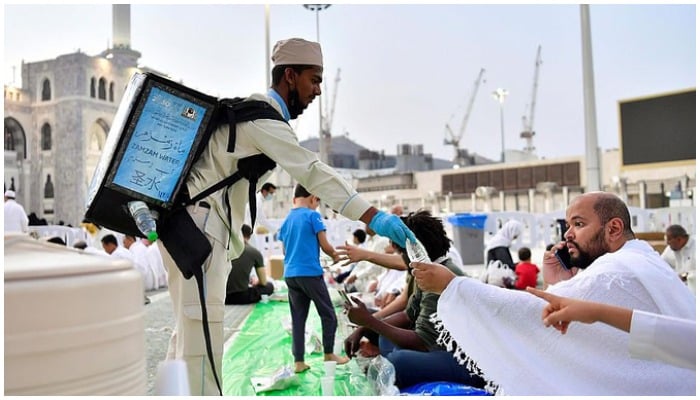 A volunteer hands over bottled water of Zamzam to a pilgrim. — Saudi Press Agency