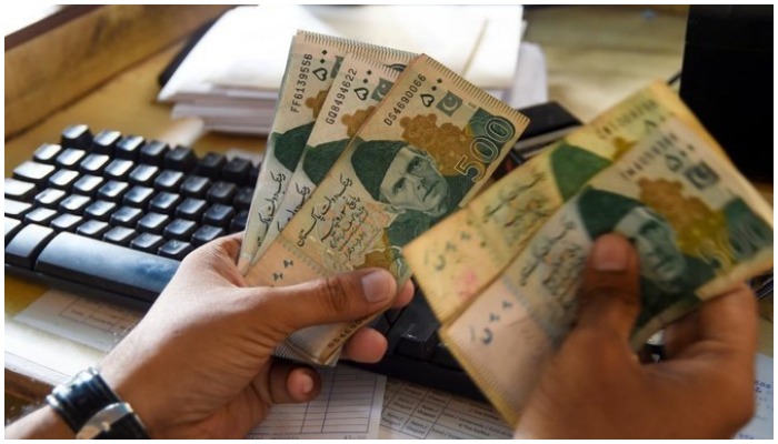 A Pakistani man counts Pakistan’s rupees at his shop in Karachi. — AFP