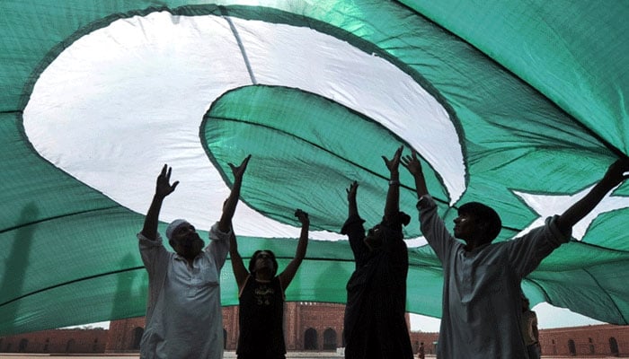 The picture shows people standing the Pakistani flag. — AFP/File