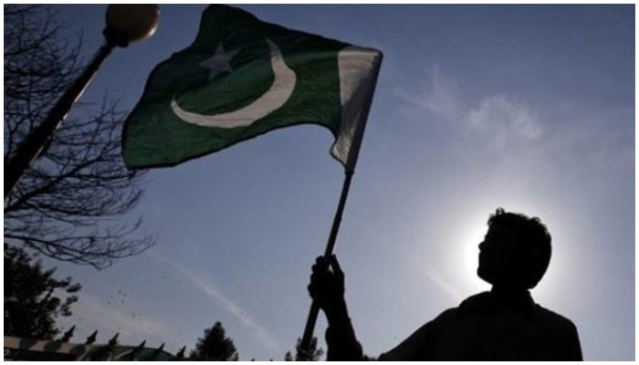 Man waves Pakistans flag. — Reuters