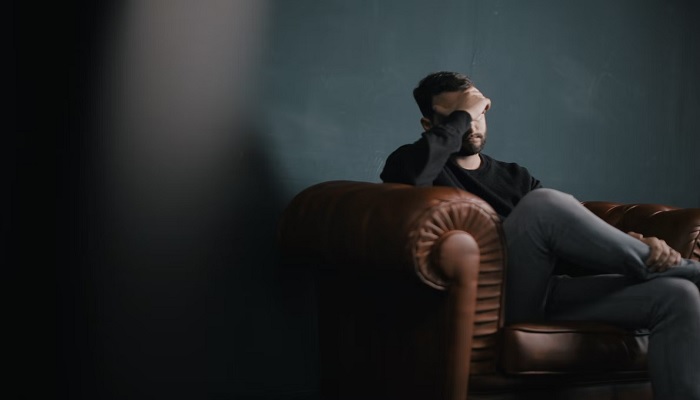 Representational image of a person sitting on a sofa with his hand covering his forehead. —Unsplash/Nik Shuliahin