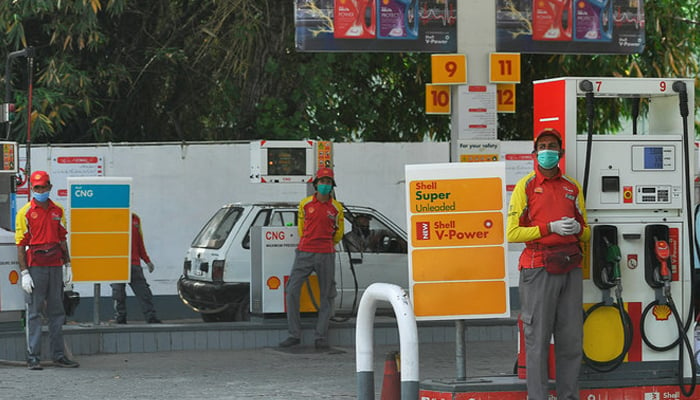 Petrol station workers wearing facemasks wait for customers next to petrol pumps in Islamabad, Pakistan, on April 22, 2020. — AFP/File