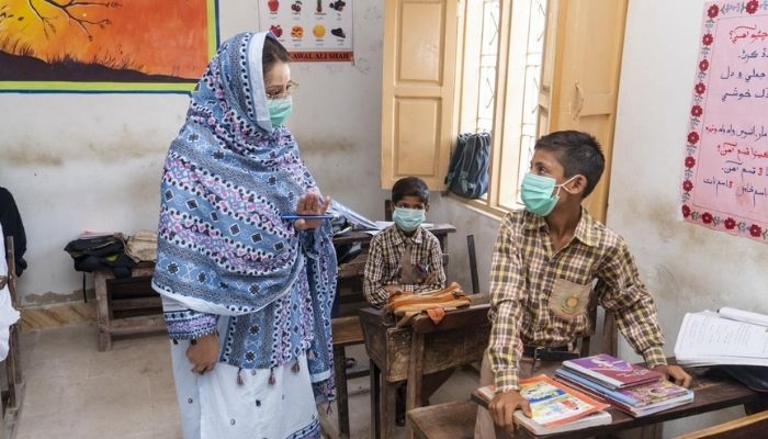 Image of teacher talking to a student in school in Pakistan — UNICEF