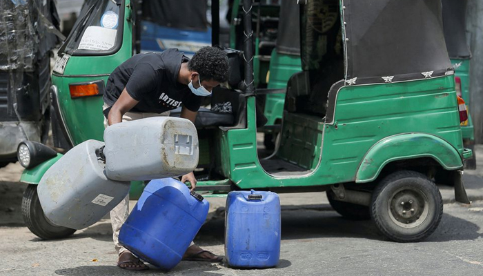 A boy tires to hold cans together as he rushes into a line to buy diesel at a Ceylon Petroleum Corporation fuel station in Colombo, Sri Lanka March 2, 2022. — Reuters