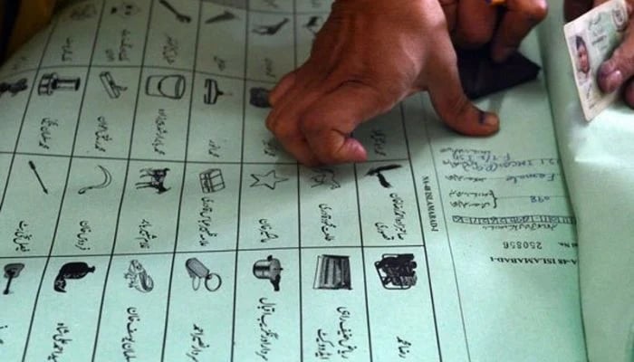 A voter imprints thumb on a voters book at a polling station in Pakistan. — AFP