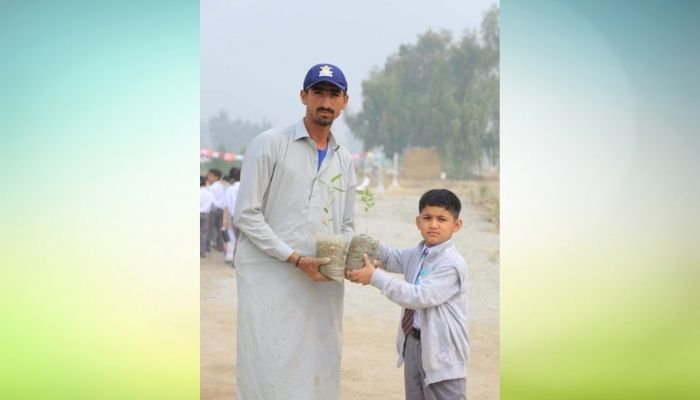 Pakistan cricket teams pacer Shahnawaz Dahani holding plant sapling with a student at an environment themed event in school.