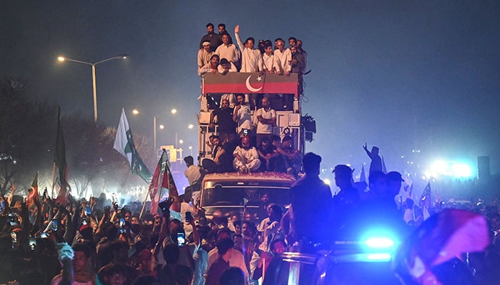 Ousted prime minister Imran Khan (C) waves to supporters from atop a bus as he leads a rally in Islamabad early on May 26, 2022. — AFP