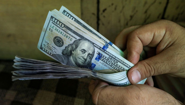 A person holds a stack of dollars. — Reuters