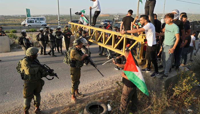 Palestinians conftont Israeli security forces after an attempt by Isreali settlers to remove Palestinian flags east of the West Bank village of Qalqiliya, on May 31, 2022. Photo — JAAFAR ASHTIYEH / AFP