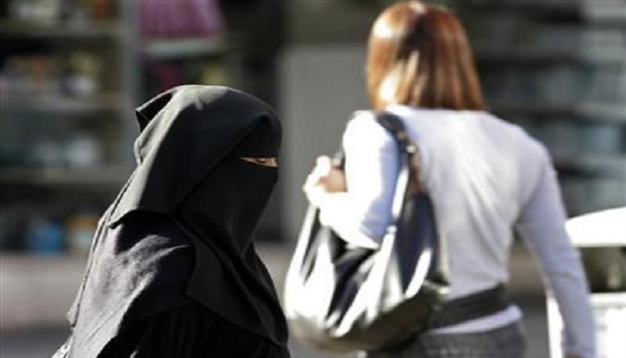 A Muslim woman wearing a veil walks along a road in the town in Blackburn, northern England, October 13, 2006. — Reuters