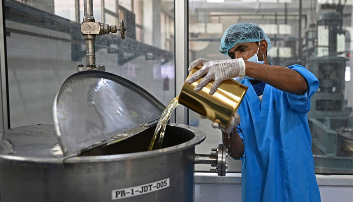 In this photograph taken on May 21, 2022, a worker adds an ingredient during the production of the Rooh Afza beverage at the Hamdard Laboratories (India) factory in Manesar. — AFP