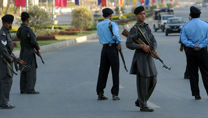 Islamabad police and security personnel stand guard at a road. — AFP